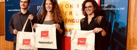 Tres participants en la iniciativa mostren bosses de roba amb el seu logotip