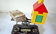 Diners i casa de joguina sobre una balança. Font: images_of_money  
(flickr.com)