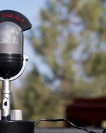 Micròfon de ràdio antic sobre una taula al mig del camp Micròfon de ràdio antic sobre una taula al mig del camp
