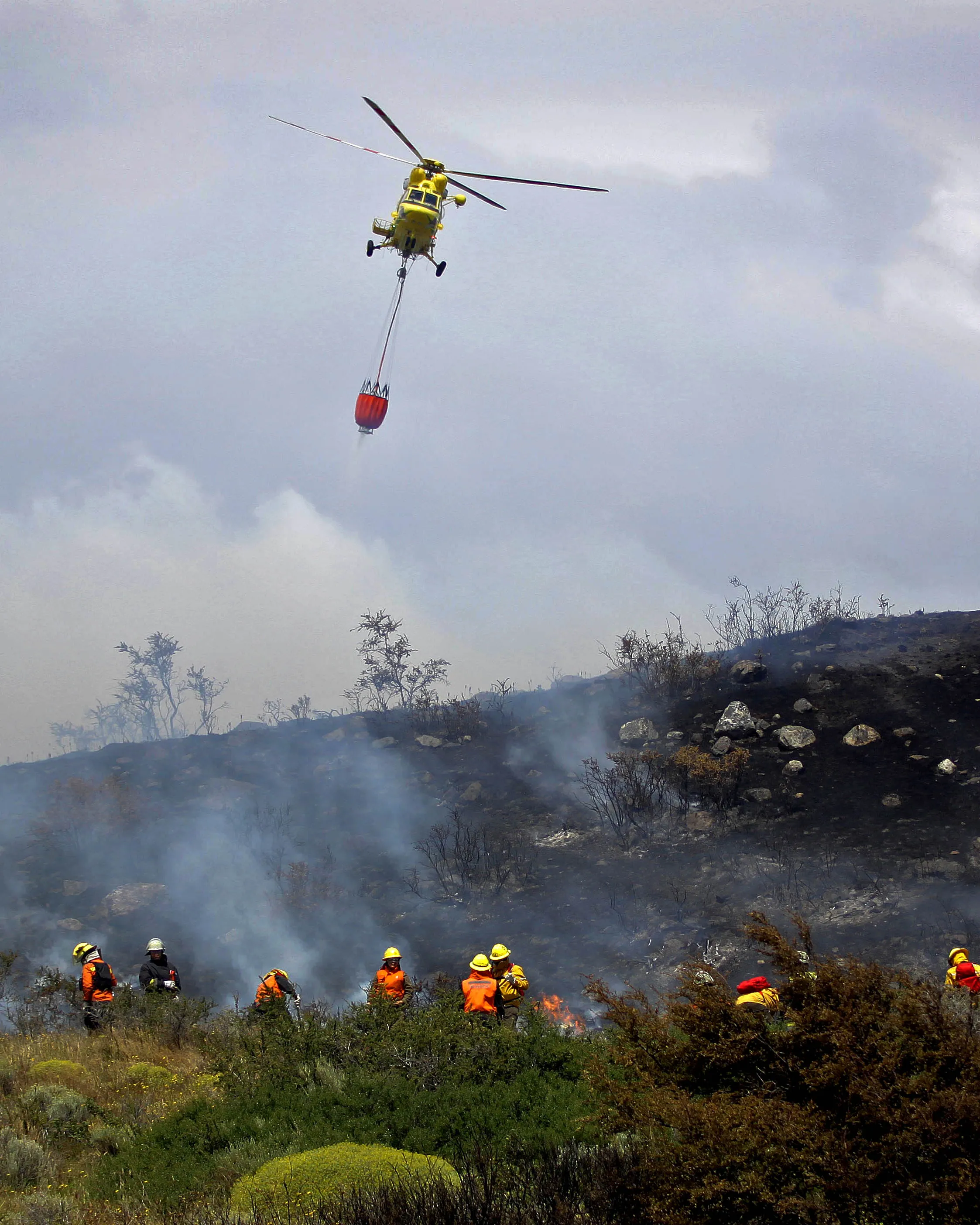 Un helicòpter amb un sac d'aigua apagant un incendi forestal