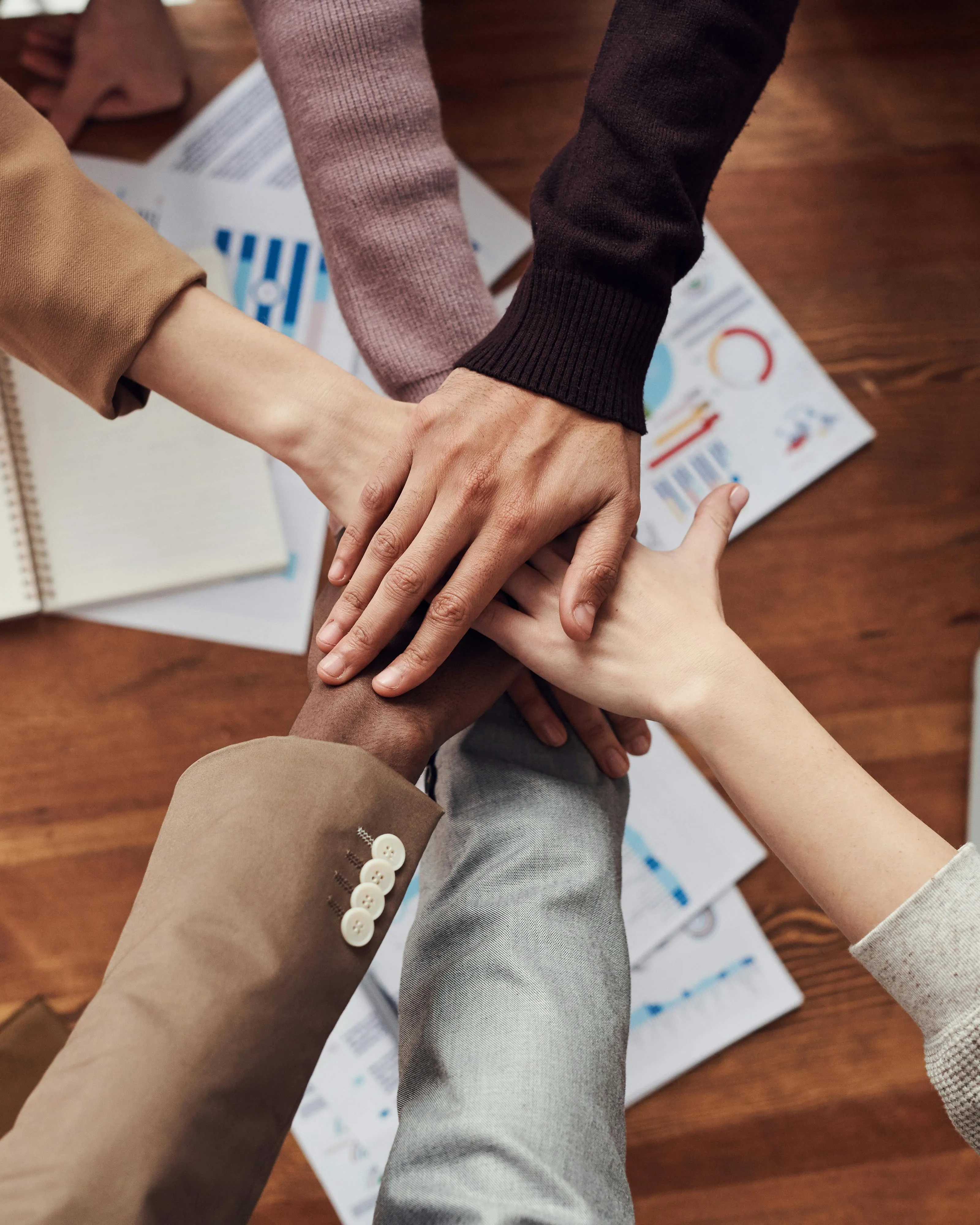Mans en cercle fent equip sobre una taula de treball