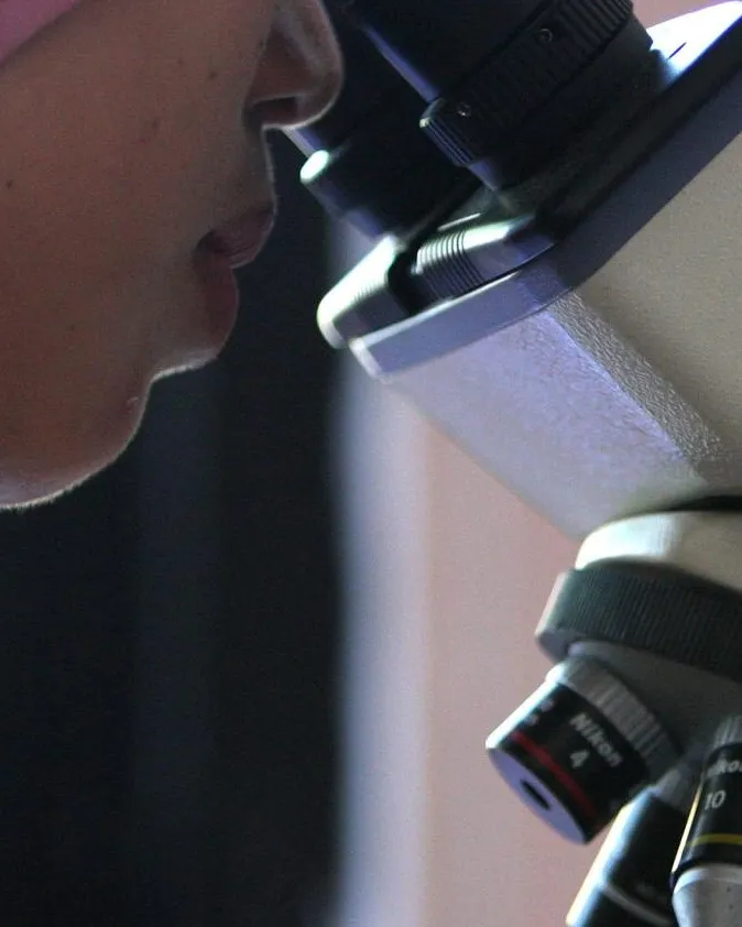 Noia mirant per un microscopi