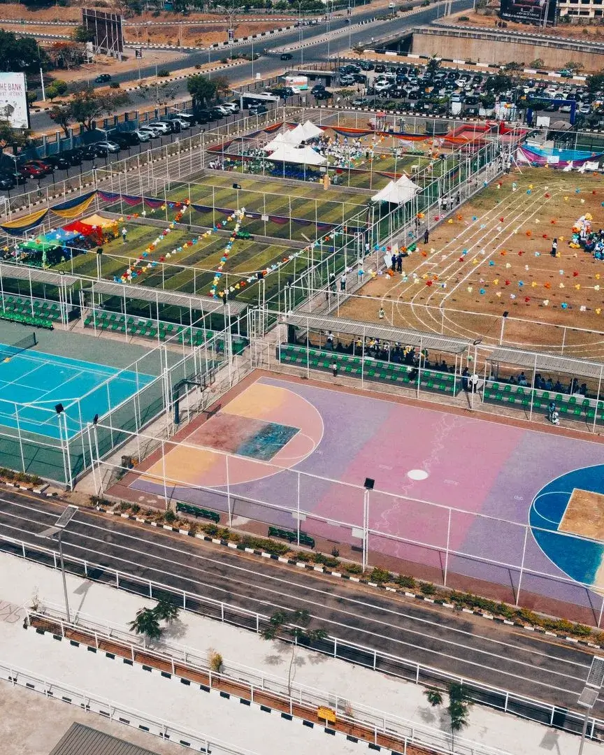 Imatge aèria d'un complex esportiu acolorit amb pistes de tennis, de bàsquet i de curses.