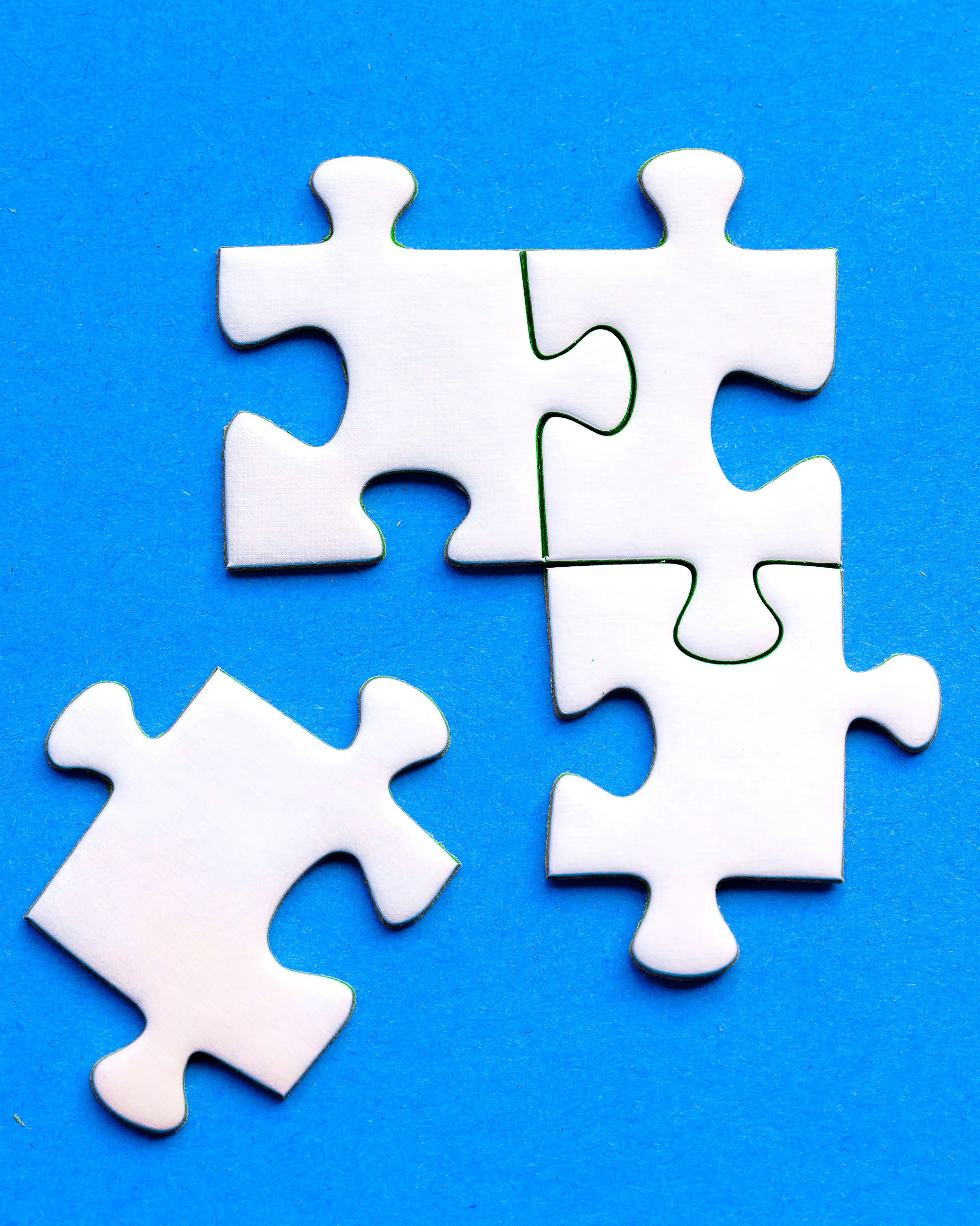 Quatre peces de puzzle, tres d'elles encaixades, sobre un fons blau. 