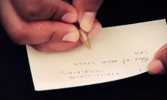 Fotograma del vídeo: una ma escriu un desig sobre la llengua