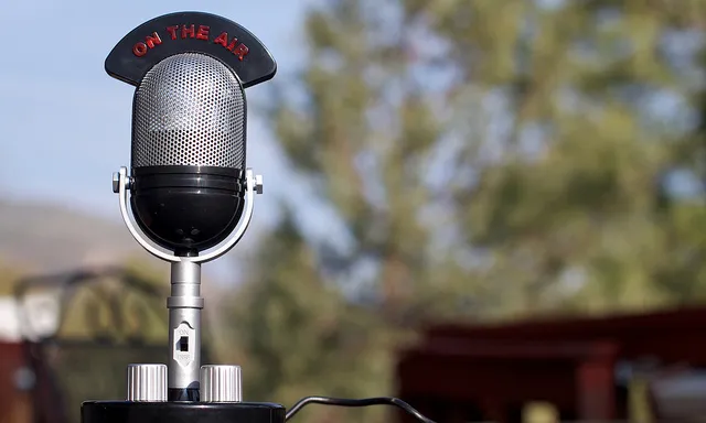 Micròfon de ràdio antic sobre una taula al mig del camp Micròfon de ràdio antic sobre una taula al mig del camp