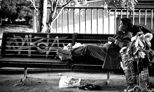 Una persona sense llar asseguda a un banc de Madrid (Font: flickr.com)