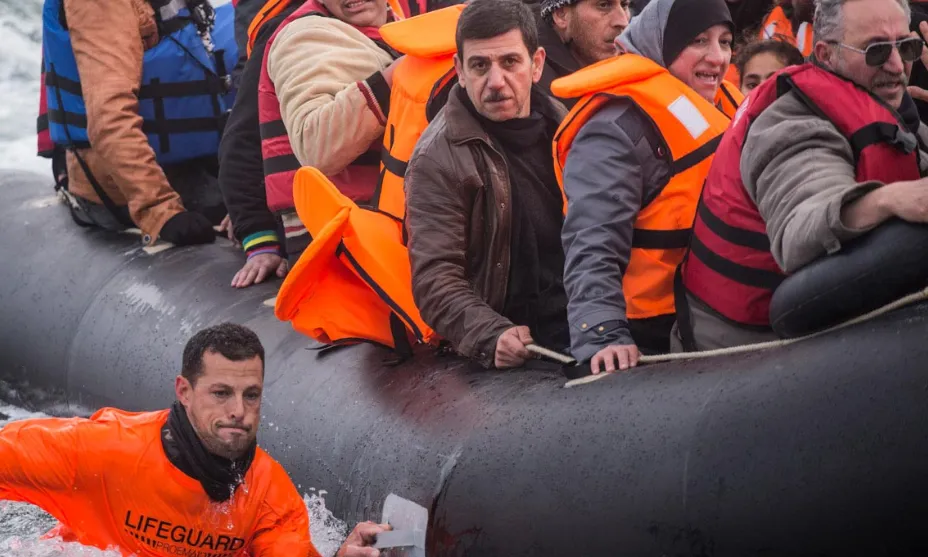 Un membre de Proemaid acompanya un bot inflable ple de persones refugiades