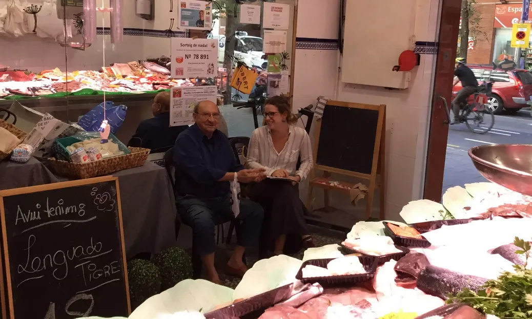 Una jove entrevista un senyor en una peixateria