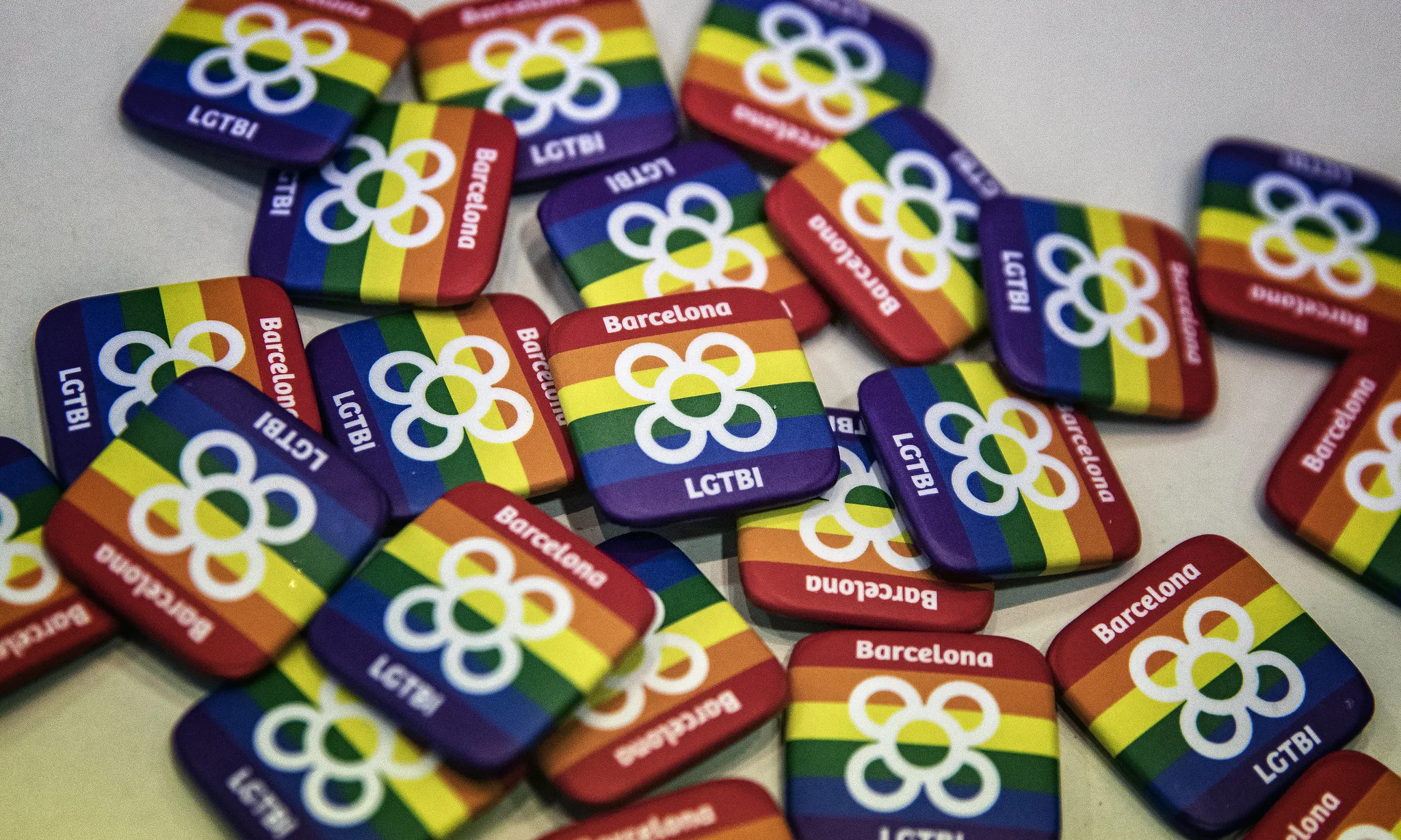 Munt de xapes amb la bandera LGTBI+ i la flor de Barcelona