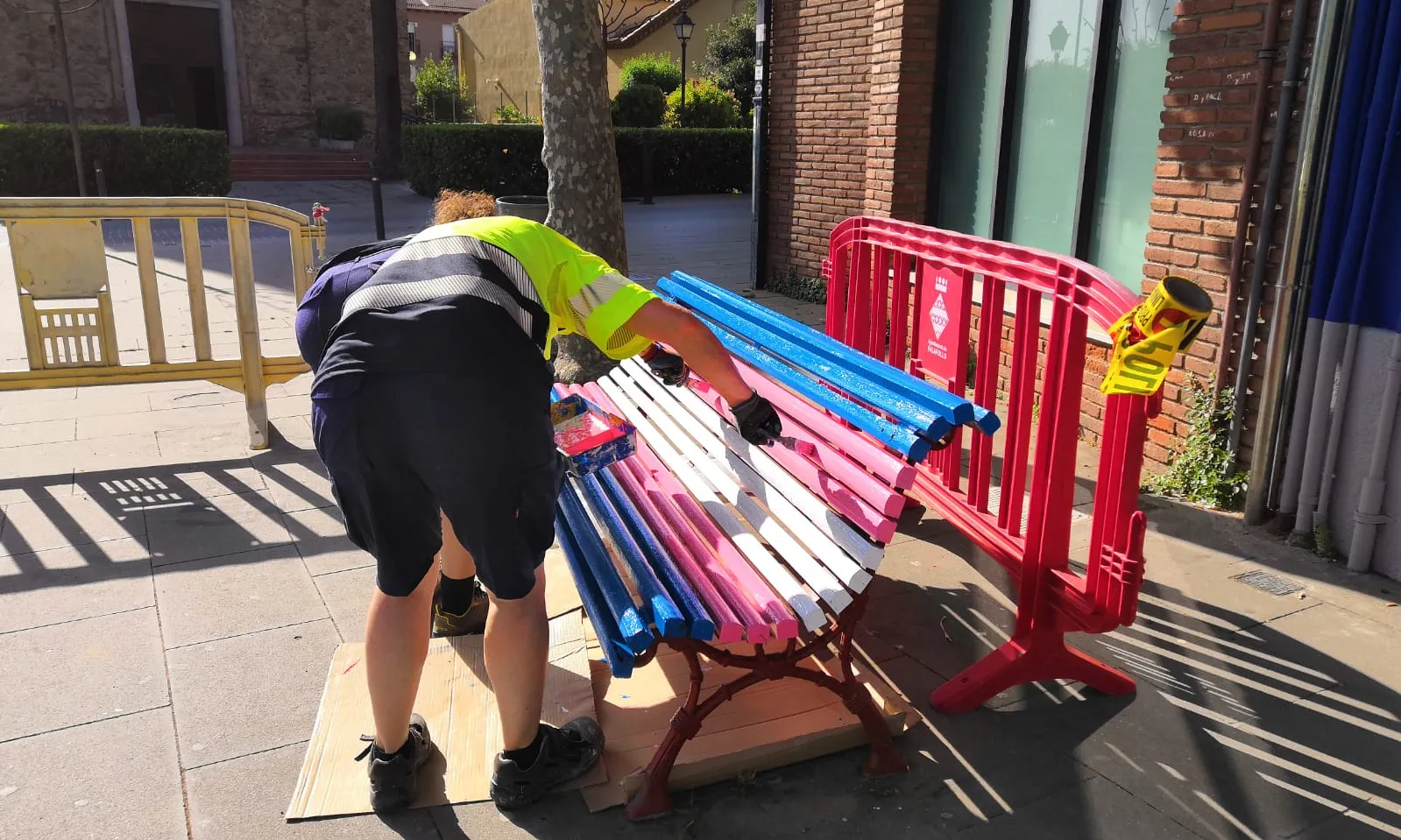 Una operària de la brigada municipal del municipi de Palafolls pinta un banc, segons marca la tradició, a primera hora del matí