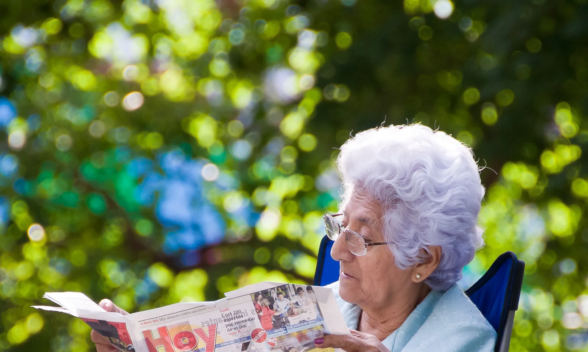 Senyora gran llegint el diari en un parc asseguda