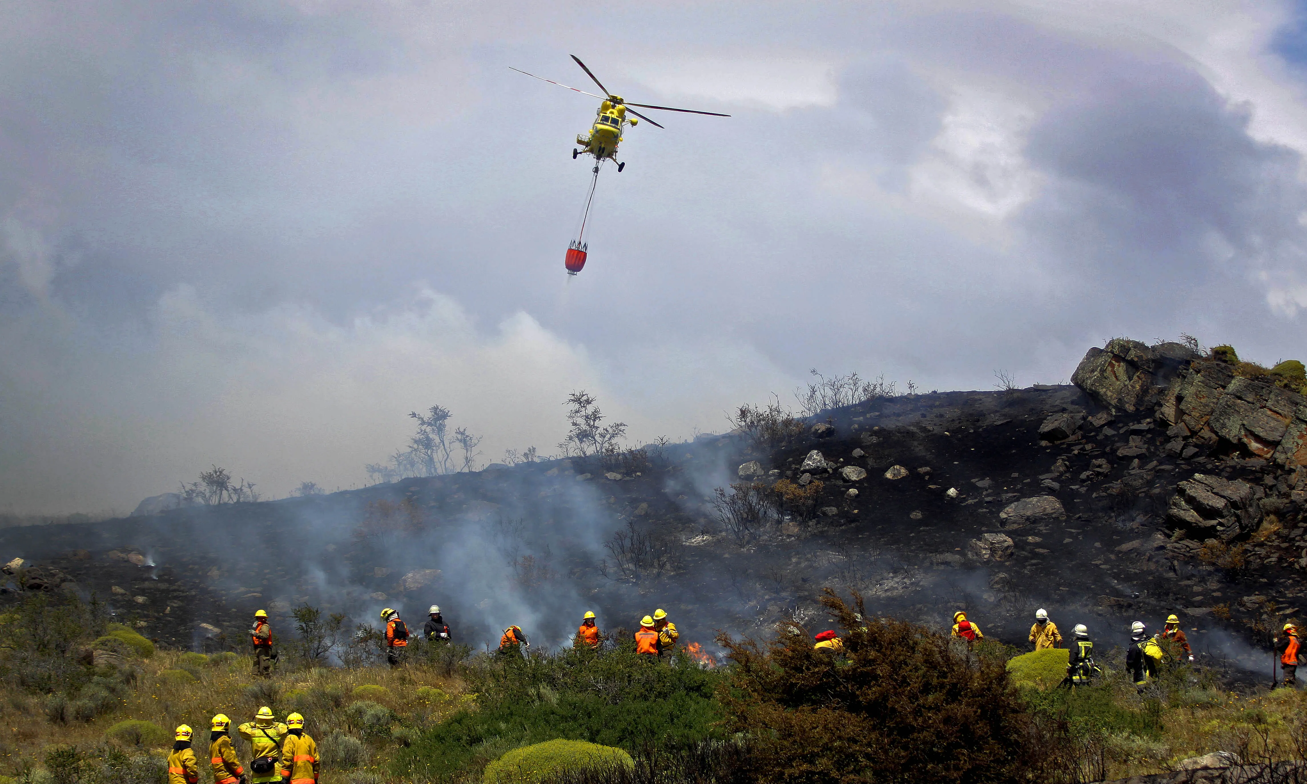 Un helicòpter amb un sac d'aigua apagant un incendi forestal