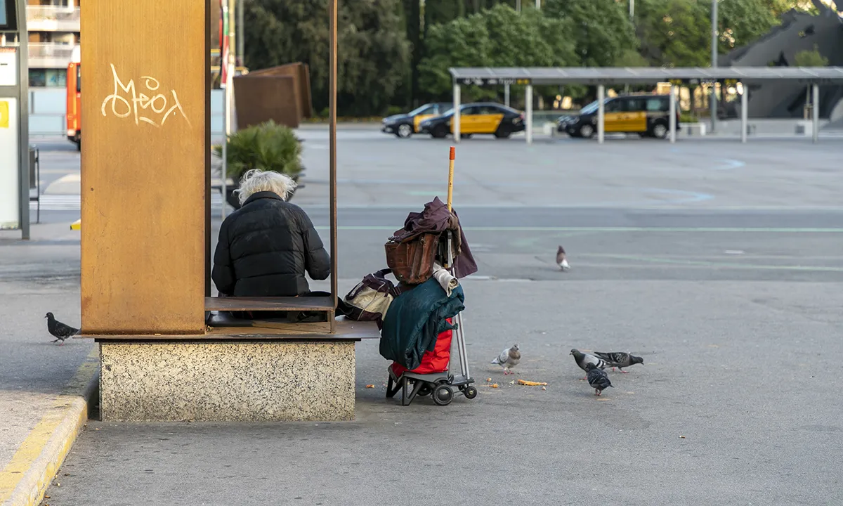 Una persona sense llar descansa en una plaça pública en ple confimanent.