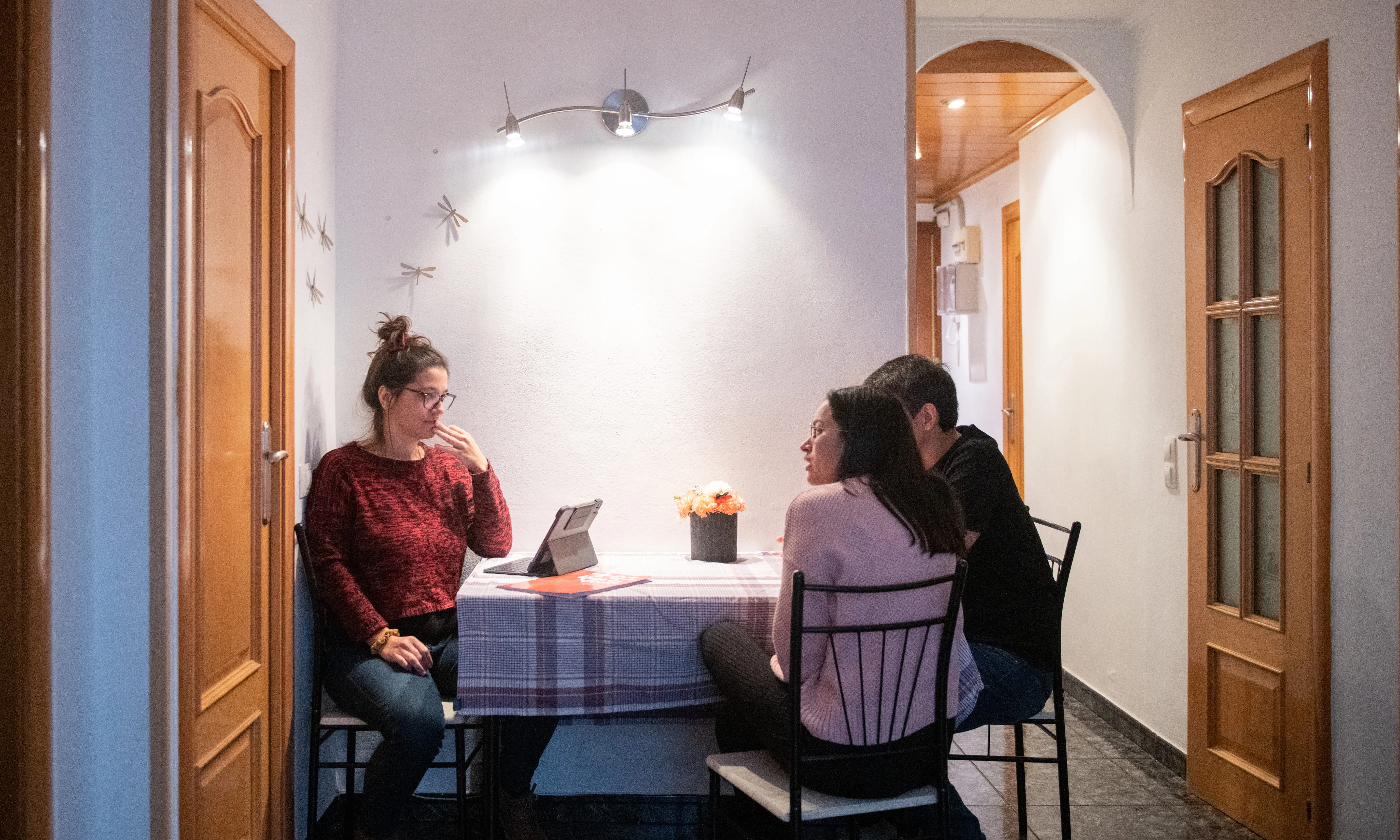 Tres persones assegudes en una taula parlant. 