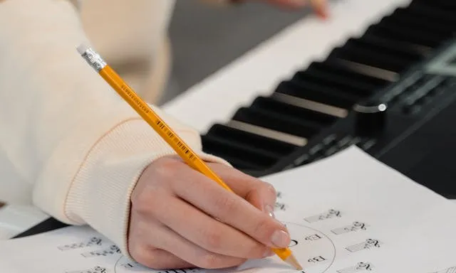 Persona amb un piano escrivint en una partitura