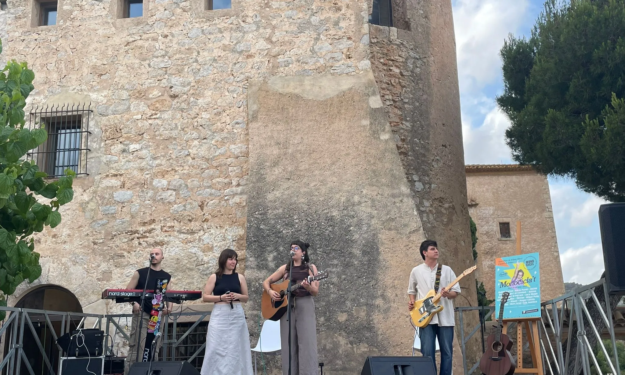 Grup de música sobre un escenari i un castell de fons.