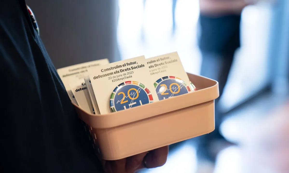 Detall d'una persona que aguanta una caixa amb xapes amb motiu de la celebració dels vint anys de la Taula del Tercer Sector Social.
