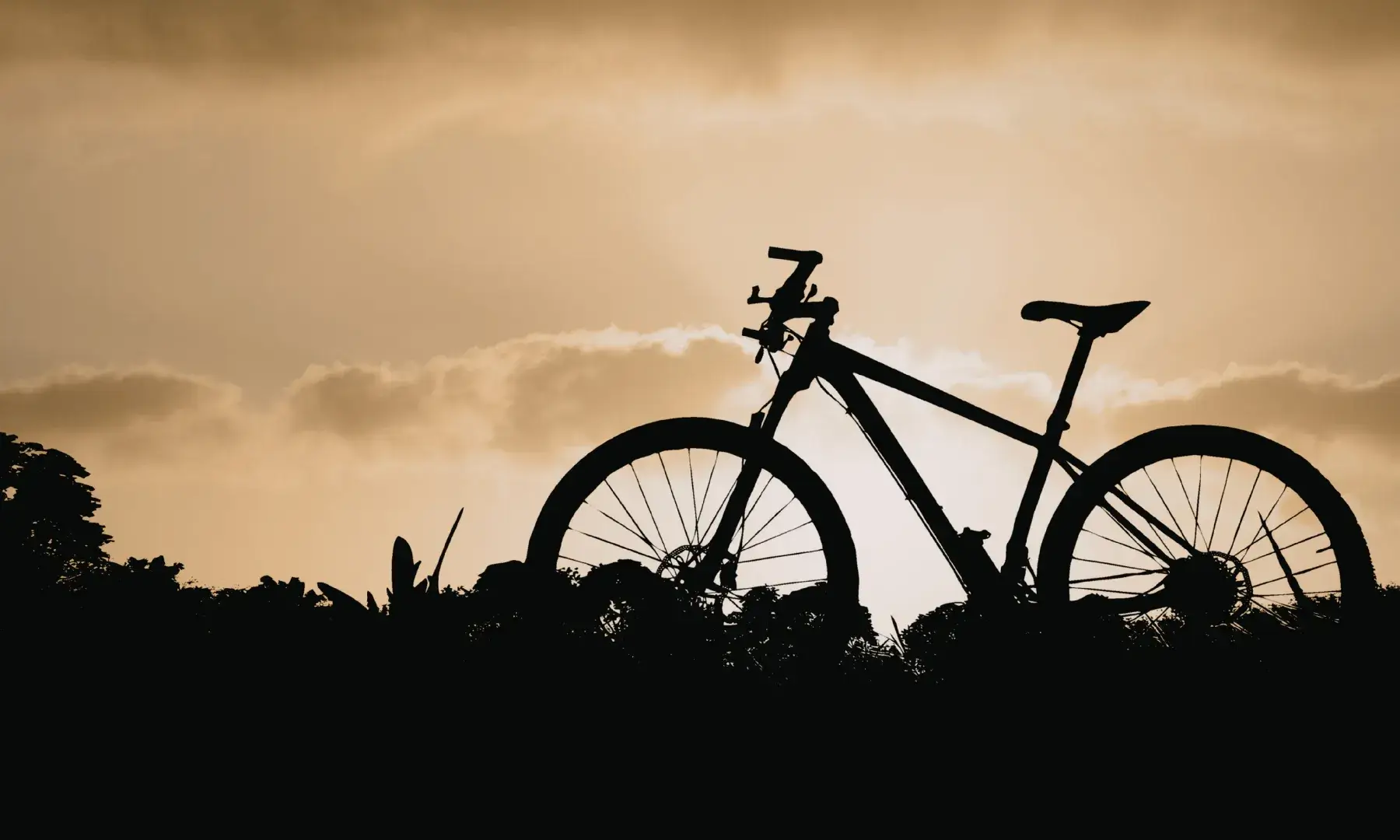 Silueta d’una bicicleta sobre un petit turó amb el cel de capvespre al fons.