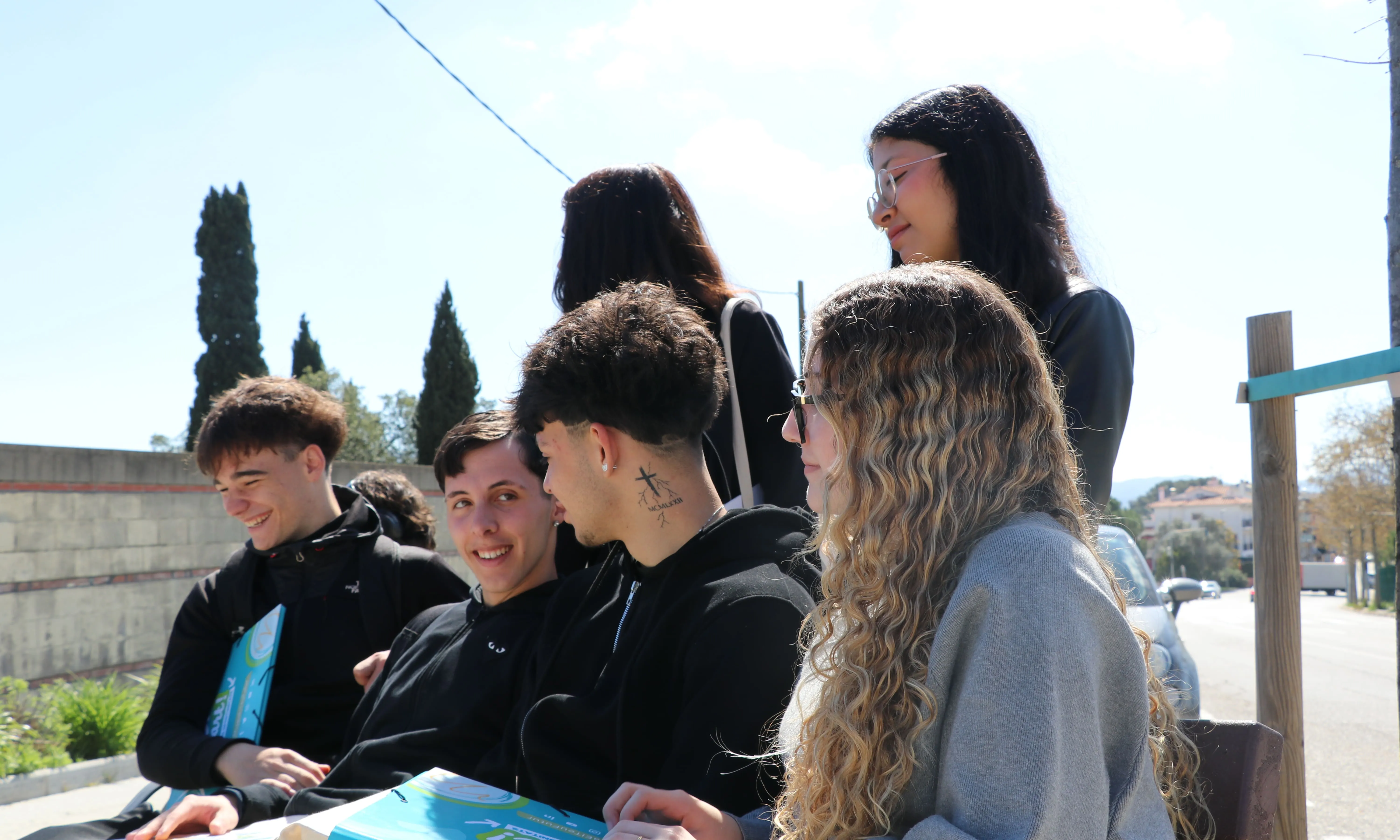 Joves participants del programa asseguts en un banc. 