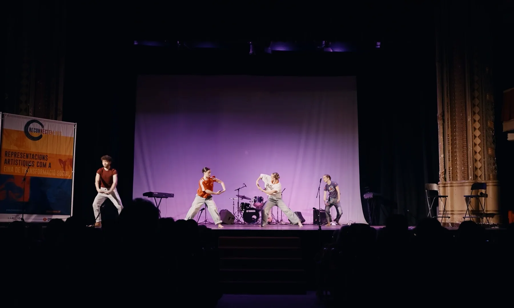 En un escenari d'un teatre es veuen un grup de persones fent dansa contemporània.
