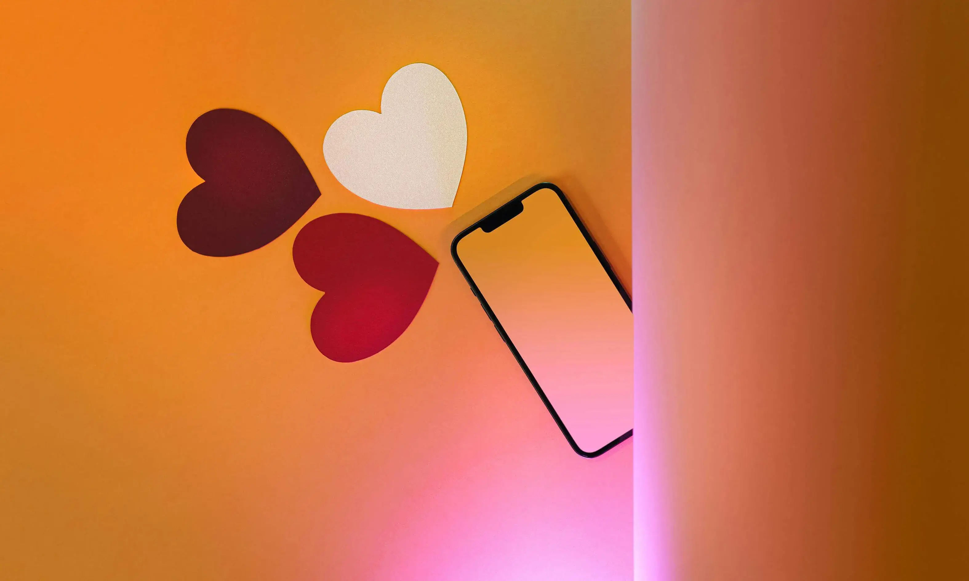 Mòbil sobre una superfície amb cors de paper al voltant. 