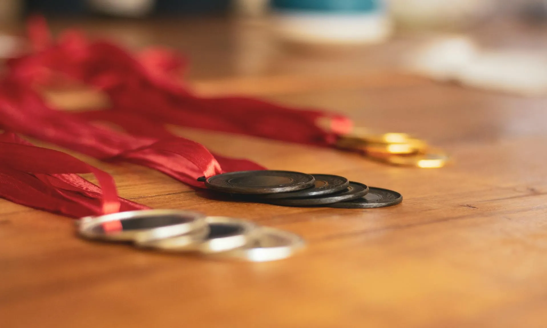 Plànol de prop de medalles d'or, plata i bronze amb cintes vermelles sobre una taula de fusta.