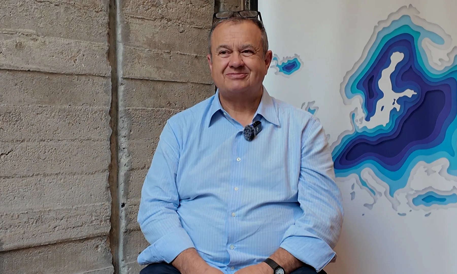 Gianluca Mengozzi assegut en una cadira mirant a càmera amb un mapa d'Europa de fons.