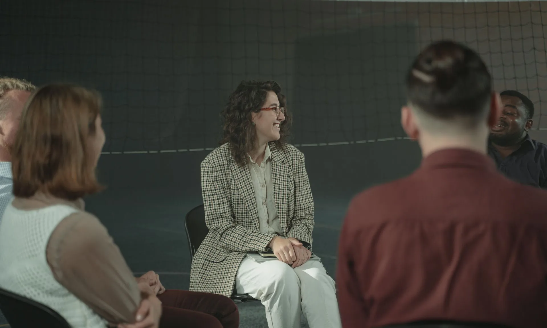 Un grup divers d'adults participava en una discussió a l'interior, asseguts en cercle.