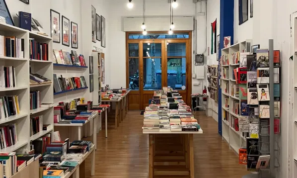 Una llibreria, fotografiada des del fons, amb estanteries i taules plenes de llibres.