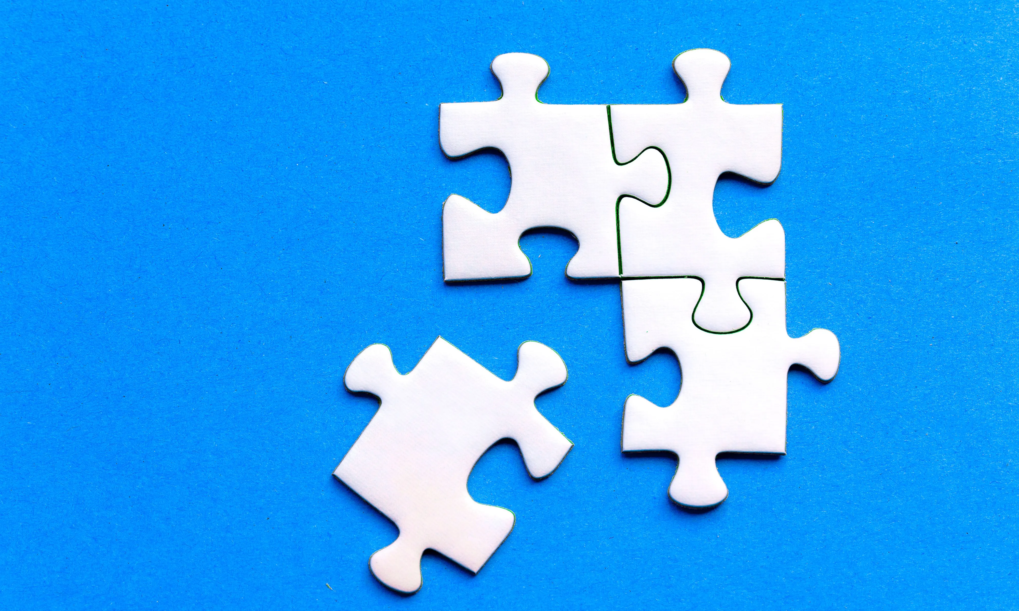 Quatre peces de puzzle, tres d'elles encaixades, sobre un fons blau. 