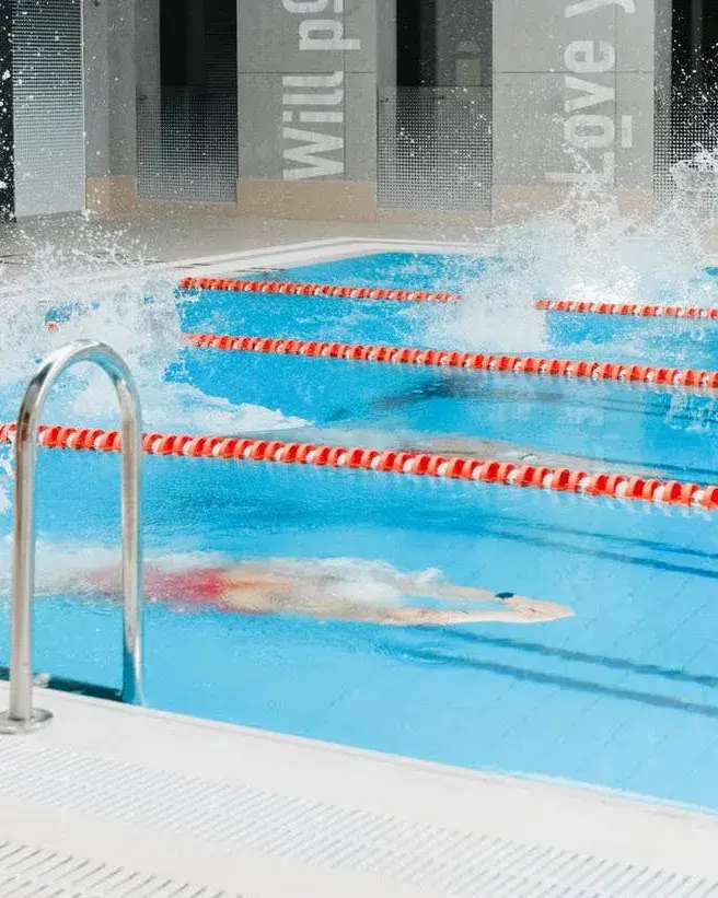 Piscina interior amb carril i nadadores fent una carrera