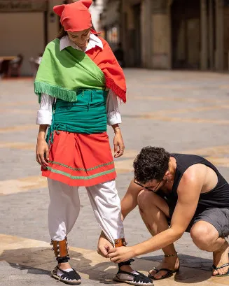 Noi ajudant a una noia a cordar les espardenyes. Font: Niu d'imatges de la joventut