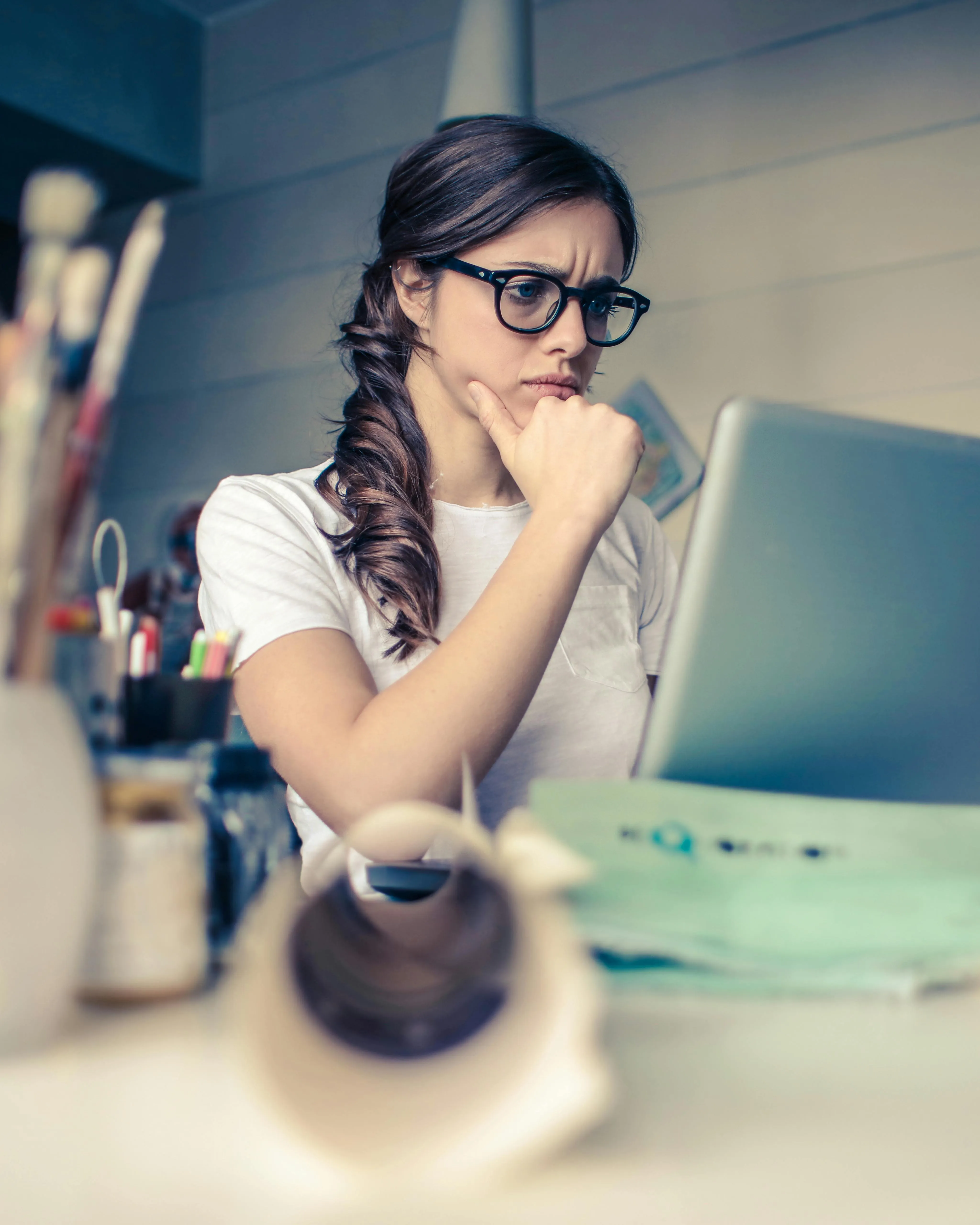 Noia amb estris de pintura mirant un ordinador. Font: Pexels - Andrea Piacquadio