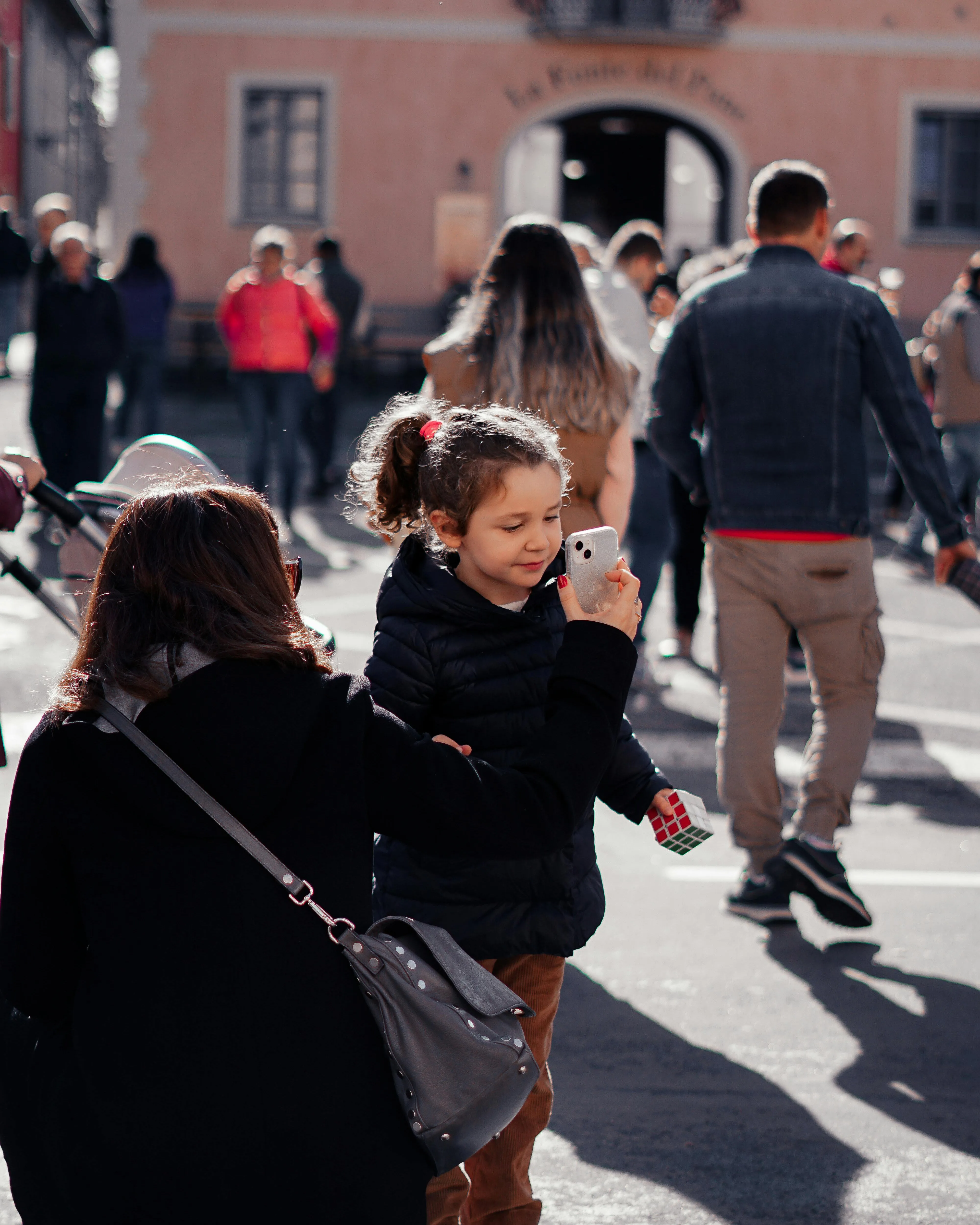 Nena mirant el mòbil que li ensenya un adult. Font: Pexels - Hardial Singh