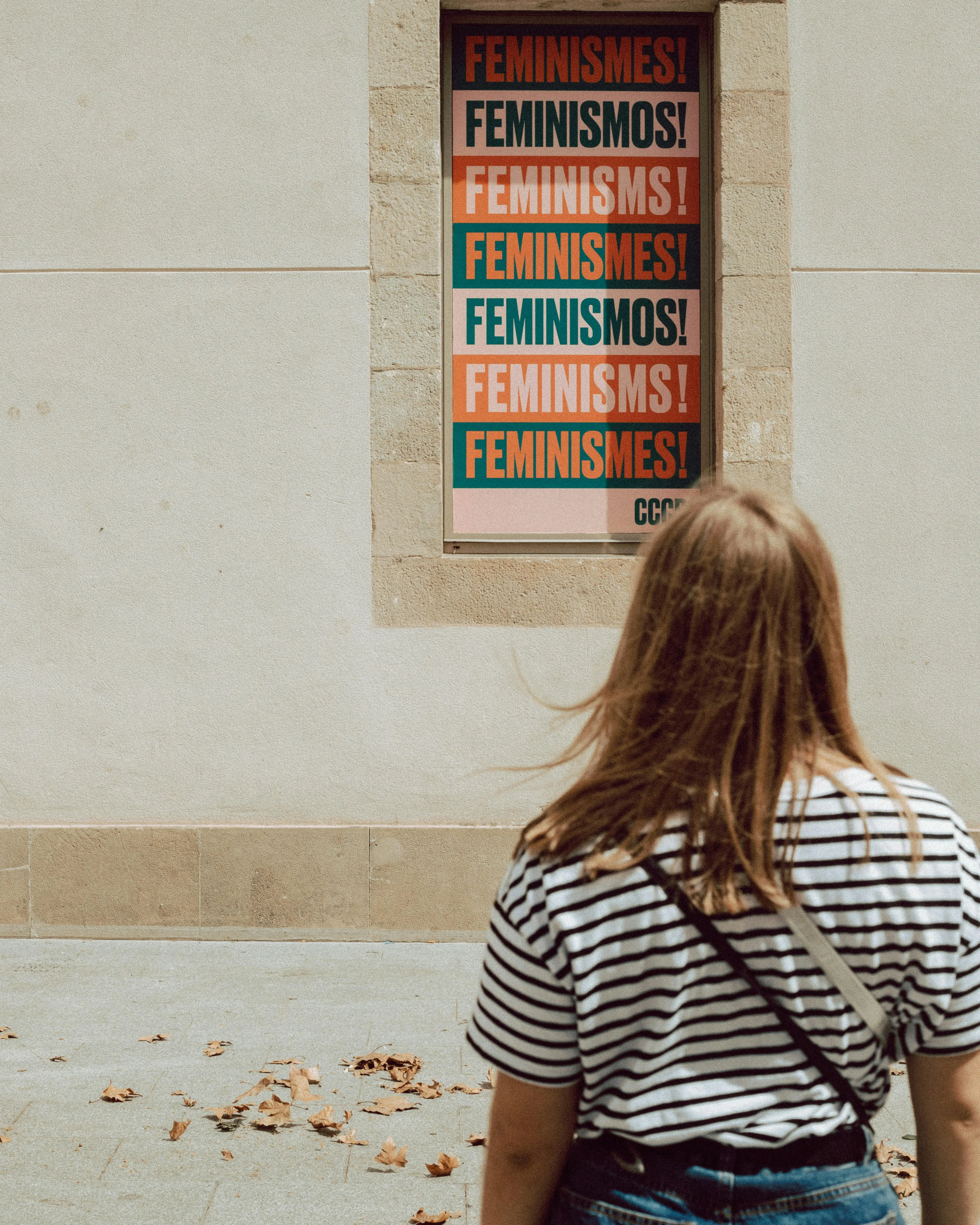Noia mirant un cartell on posa feminisme en diferents idiomes. Font: Pexels - Sinitta Leunen