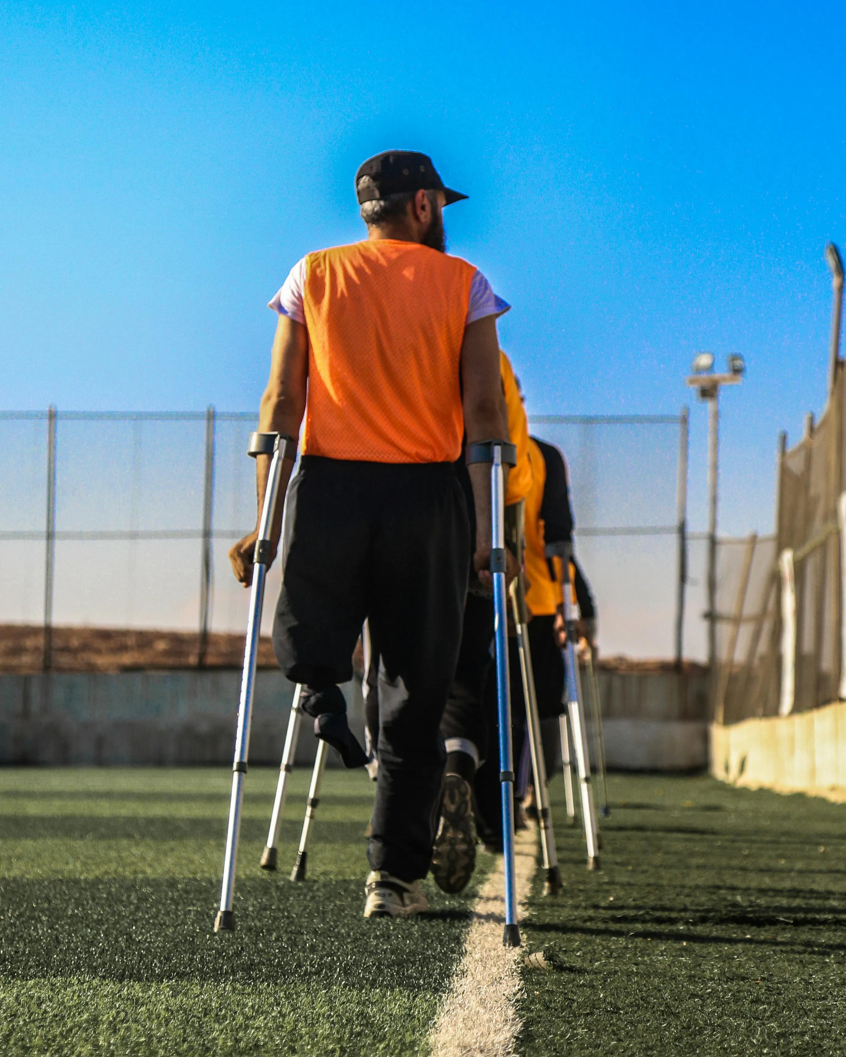 Persones amb croces en un camp de fútbol. Font: Pexels - Anas Aldyab