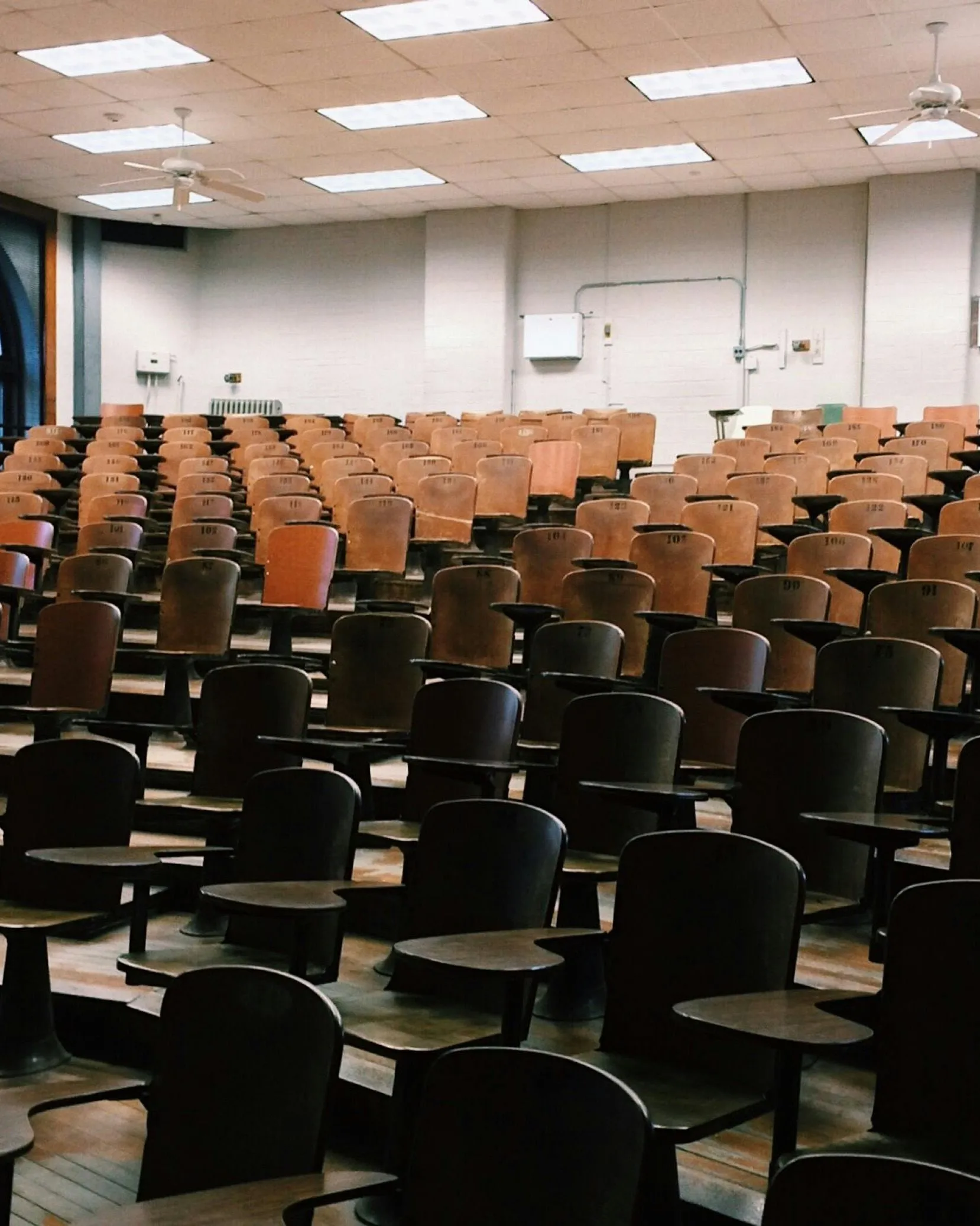 Aula universitària amb cadires de fusta tipus amfiteatre buida