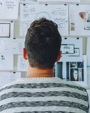 Home observant una paret on hi pengen fulles amb dades i idees