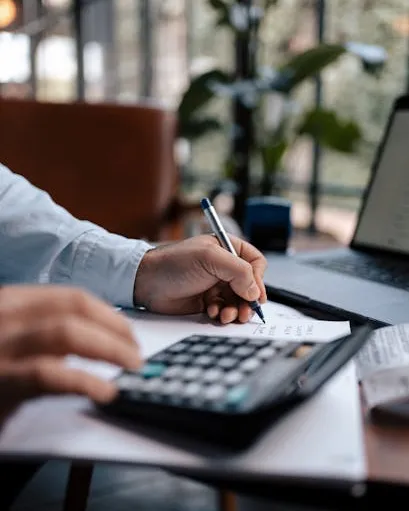 Economia Persona amb una calculadora apuntant dades en un full