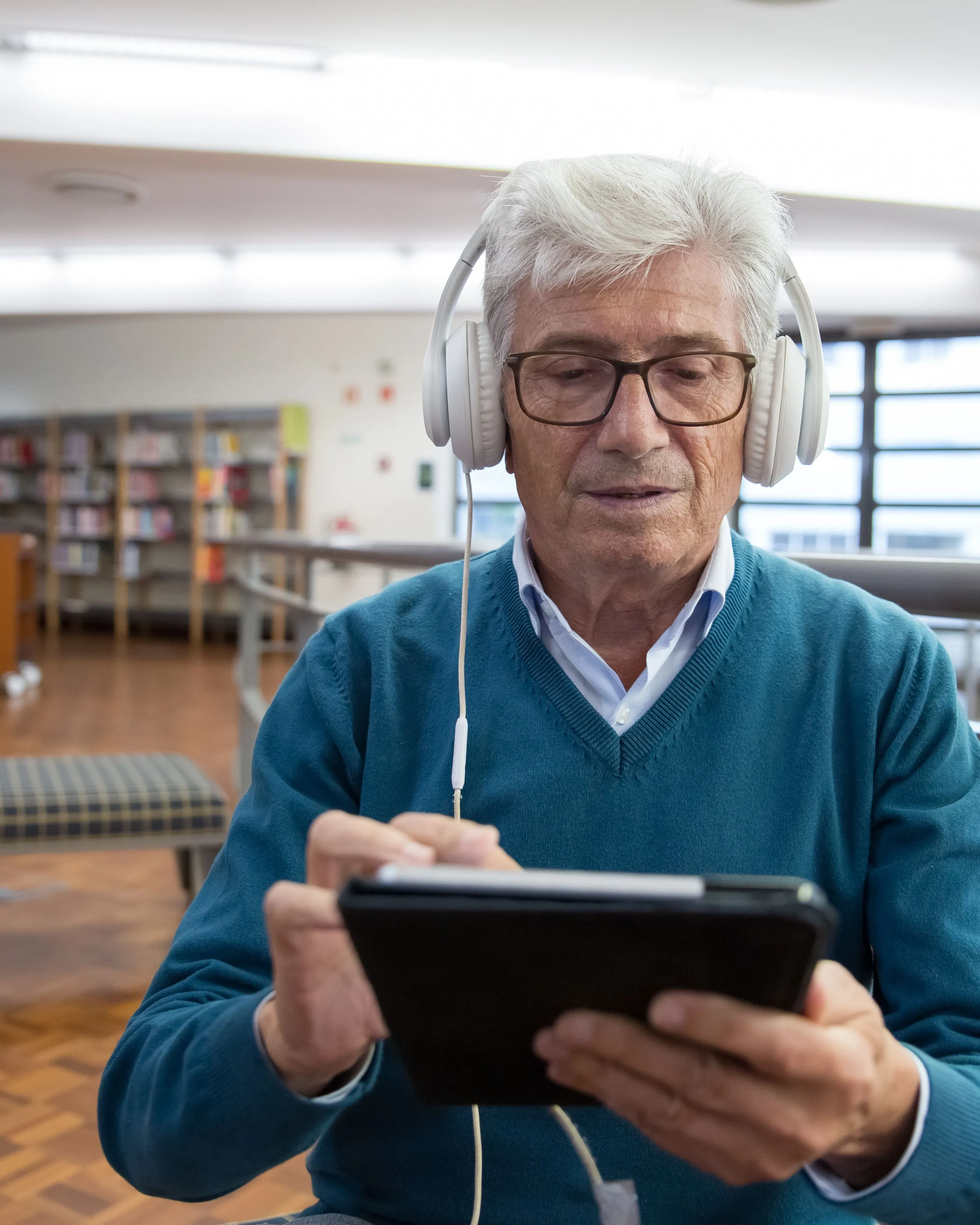 Persona escoltant un audiollibre amb auriculars i un dispositiu electrònic.