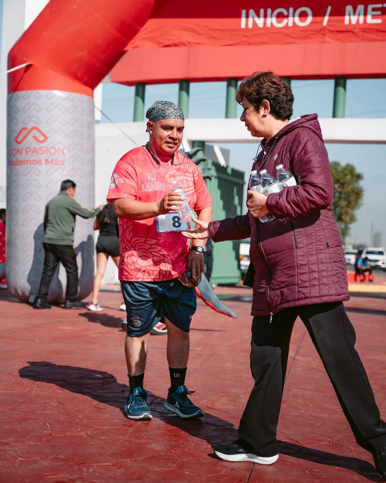 Un corredor adult rep aigua a la línia de meta d'una marató d'una voluntària.
