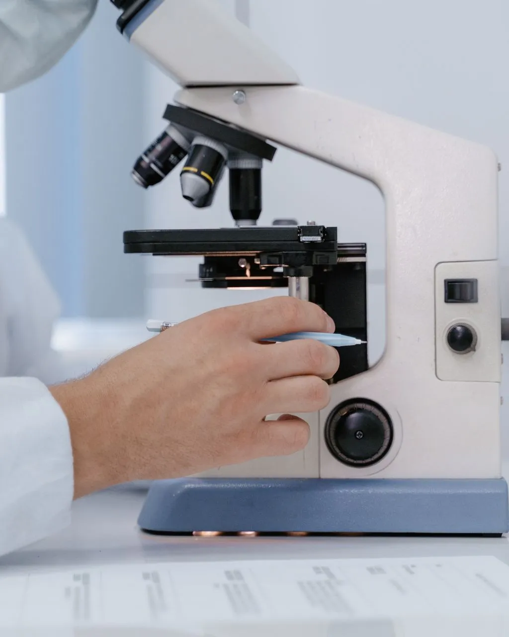 Investigador analitzant mostres amb un microscopi en un entorn de laboratori.