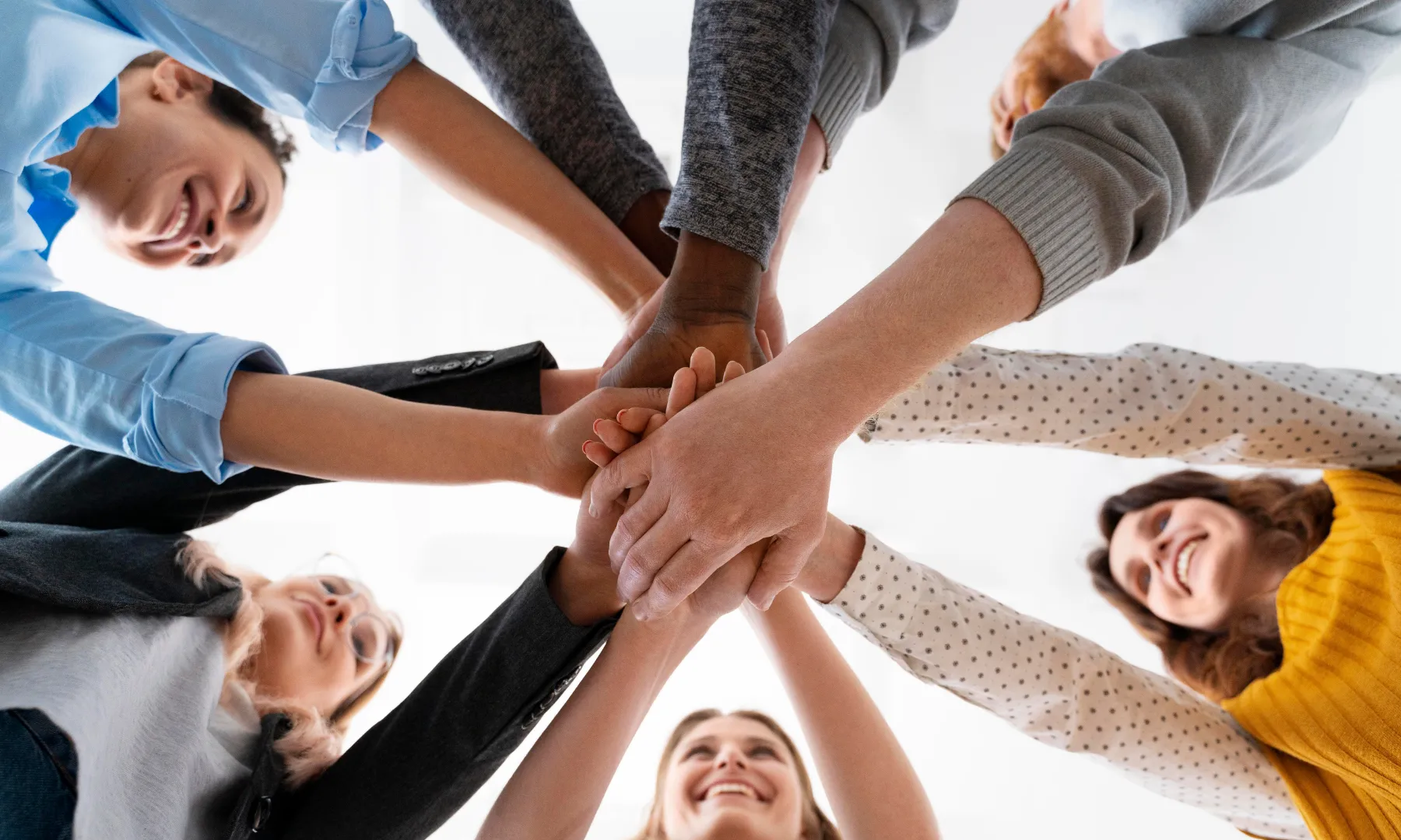 Grup de persones posant les mans juntes en senyal de cooperació i treball en equip.