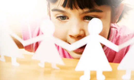 Nena mirant uns papers que simbolitzen una familia. Font: familiayadopción.com