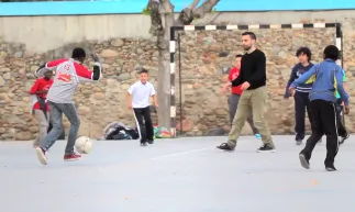 Jove voluntari jugant a futbol amb adolescents en un camp a Salt (Font: OCD de la UdG)