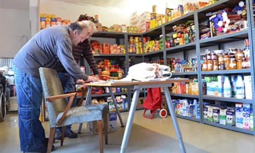 Dues persones voluntàries del centre El Caliu gestionant el rebost i les donacions d'aliments