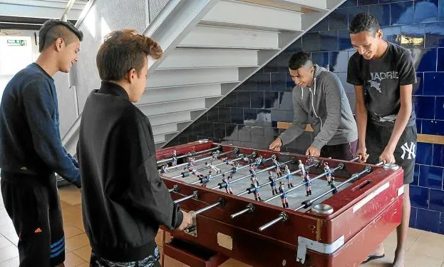 Quatre adolescents del centre Estrep, fent temps un matí jugant al futbolí, abans no comencin les classes