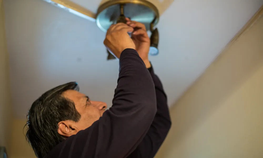 Un home canviant una bombeta de casa