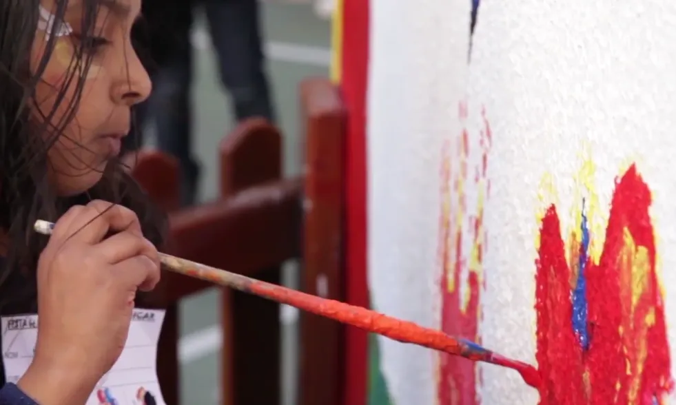 Una nena participant del projecte "Vincular x educar" pintant dibuixos la paret 